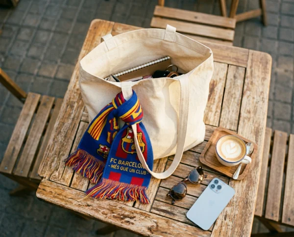 A colorful club scarf tied to a canvas tote bag at a sidewalk cafe.